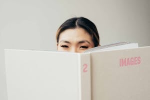 Young female reading book on white background